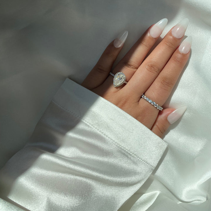 Hand wearing two rings on a white fabric background