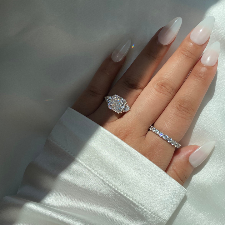 Hand wearing two diamond rings with a light background