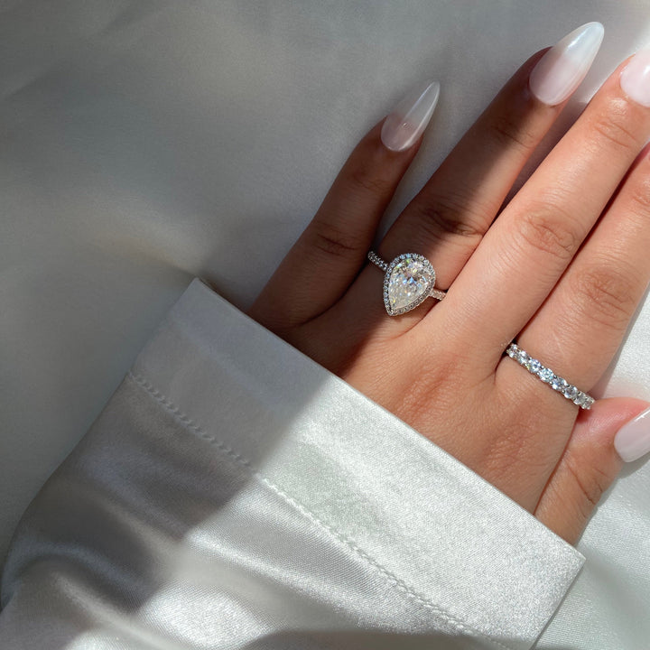 Close-up of a hand wearing two diamond rings on a light background