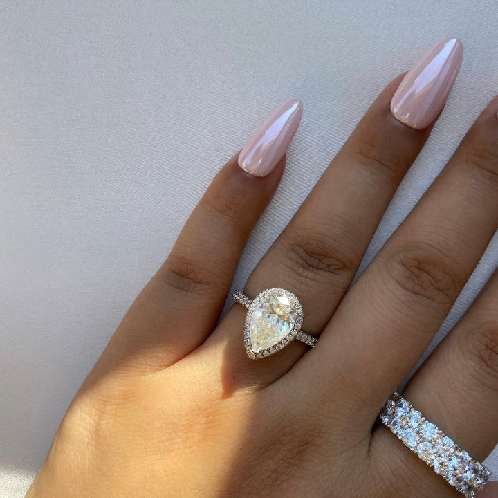 Hand wearing a diamond ring on a light background